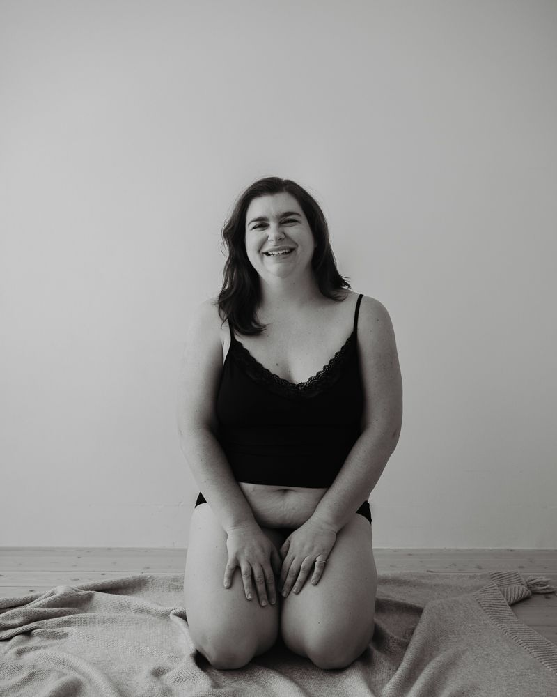 Black and white portrait of woman in casual attire kneeling on a blanket.