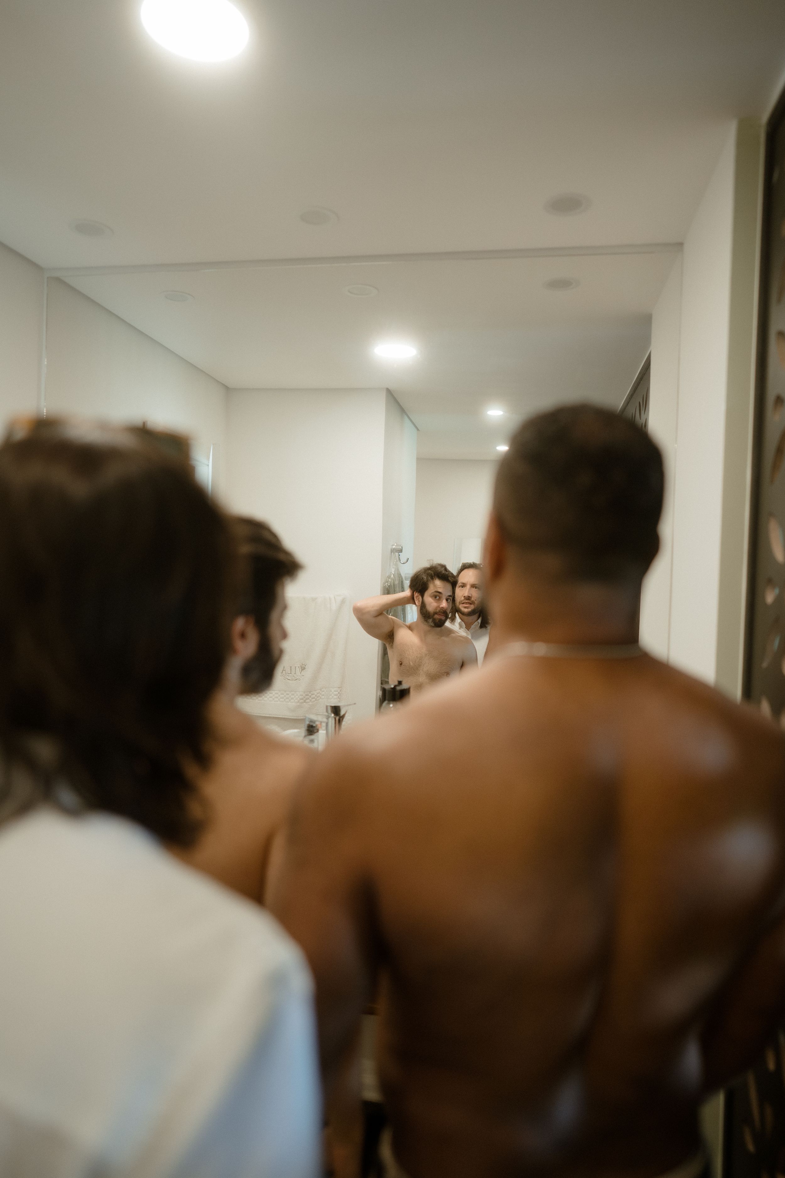 A candid wedding preparation moment captured in a bathroom mirror reflection.