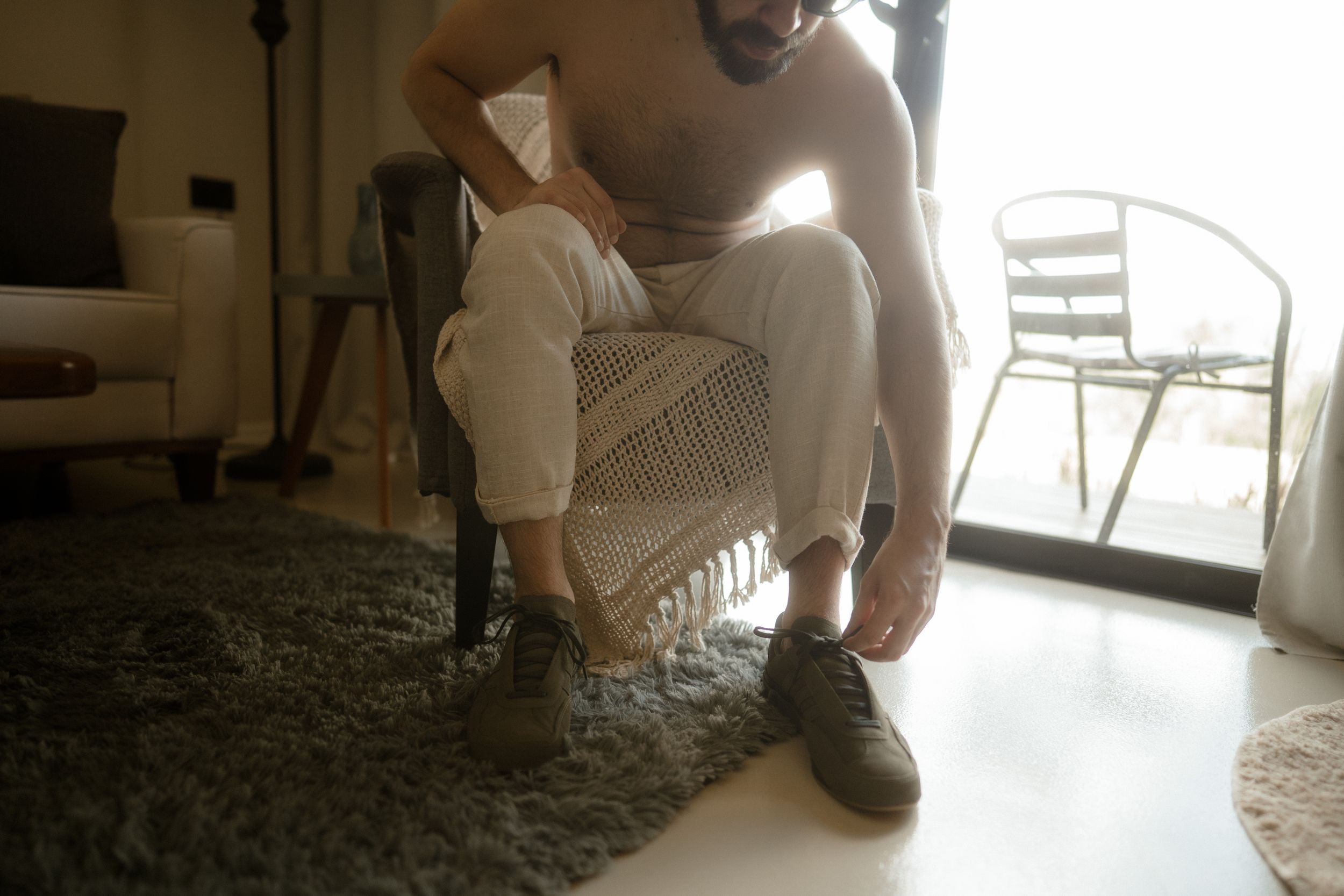 Close-up view of someone putting on formal shoes and white pants.