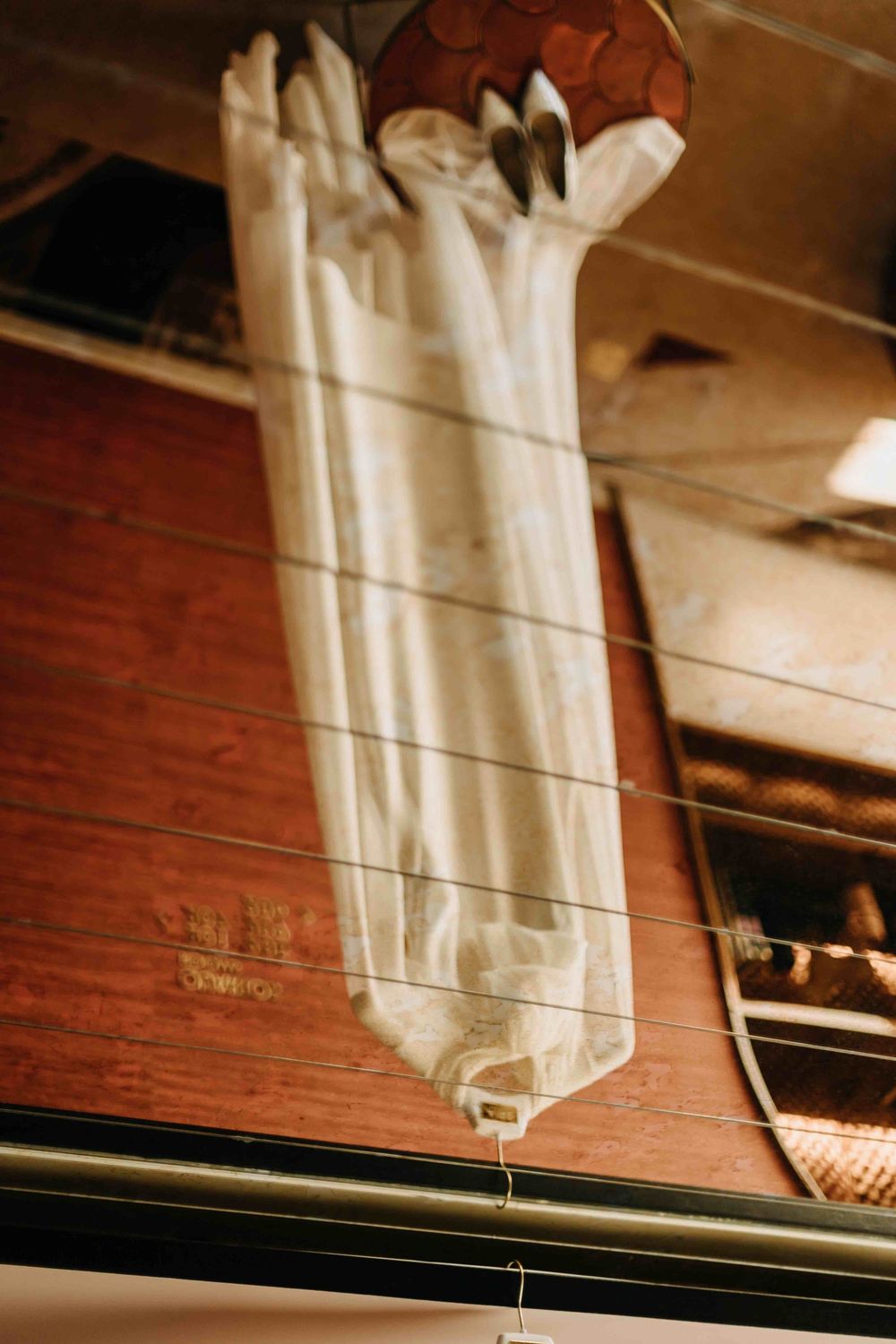 Long white gloves hanging on display against a warm wooden surface under soft lighting in a vintage-style setting.