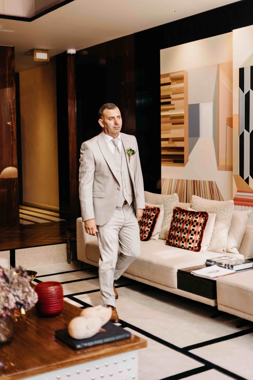 Interior scene showing a contemporary living room with modern artwork, beige sectional sofa and wooden accent decor.