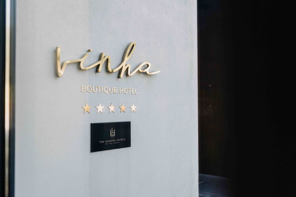 Modern art pieces hang on a sleek white wall with elegant script lettering and minimalist lighting design.