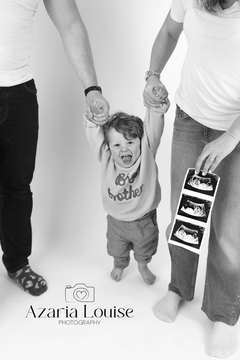 Black and white pregnancy announcement photo showing parents holding child's hands with ultrasound images.
