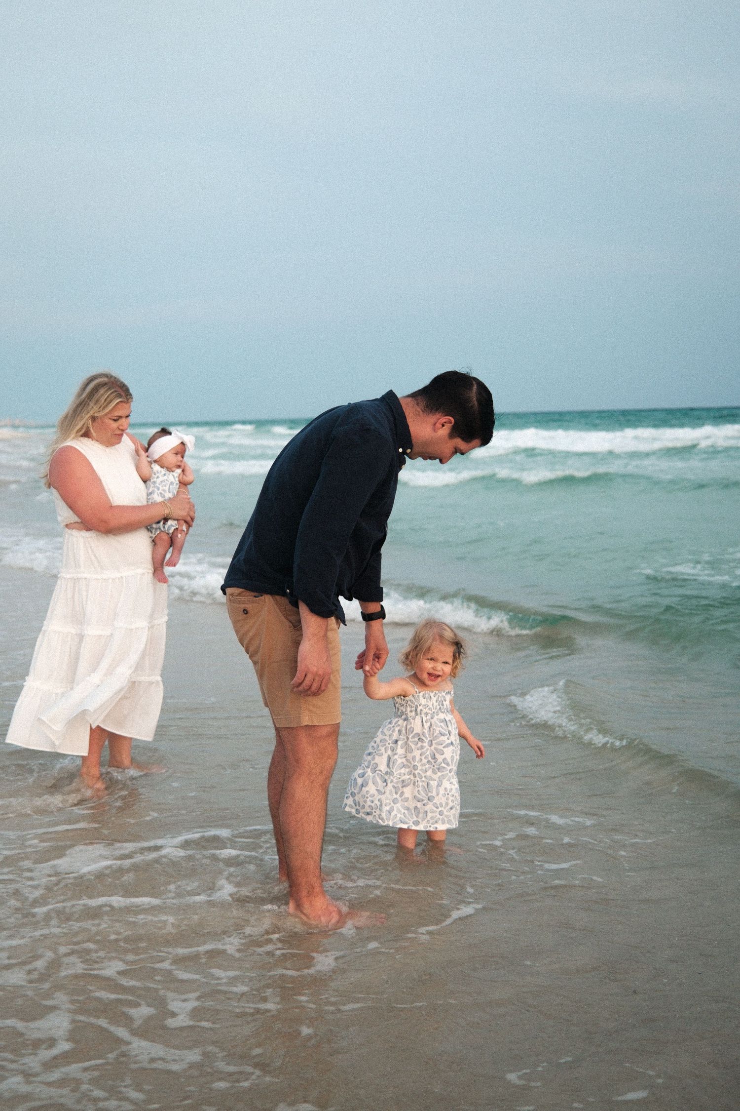 Family enjoying time together at the beach's edge as waves roll in.