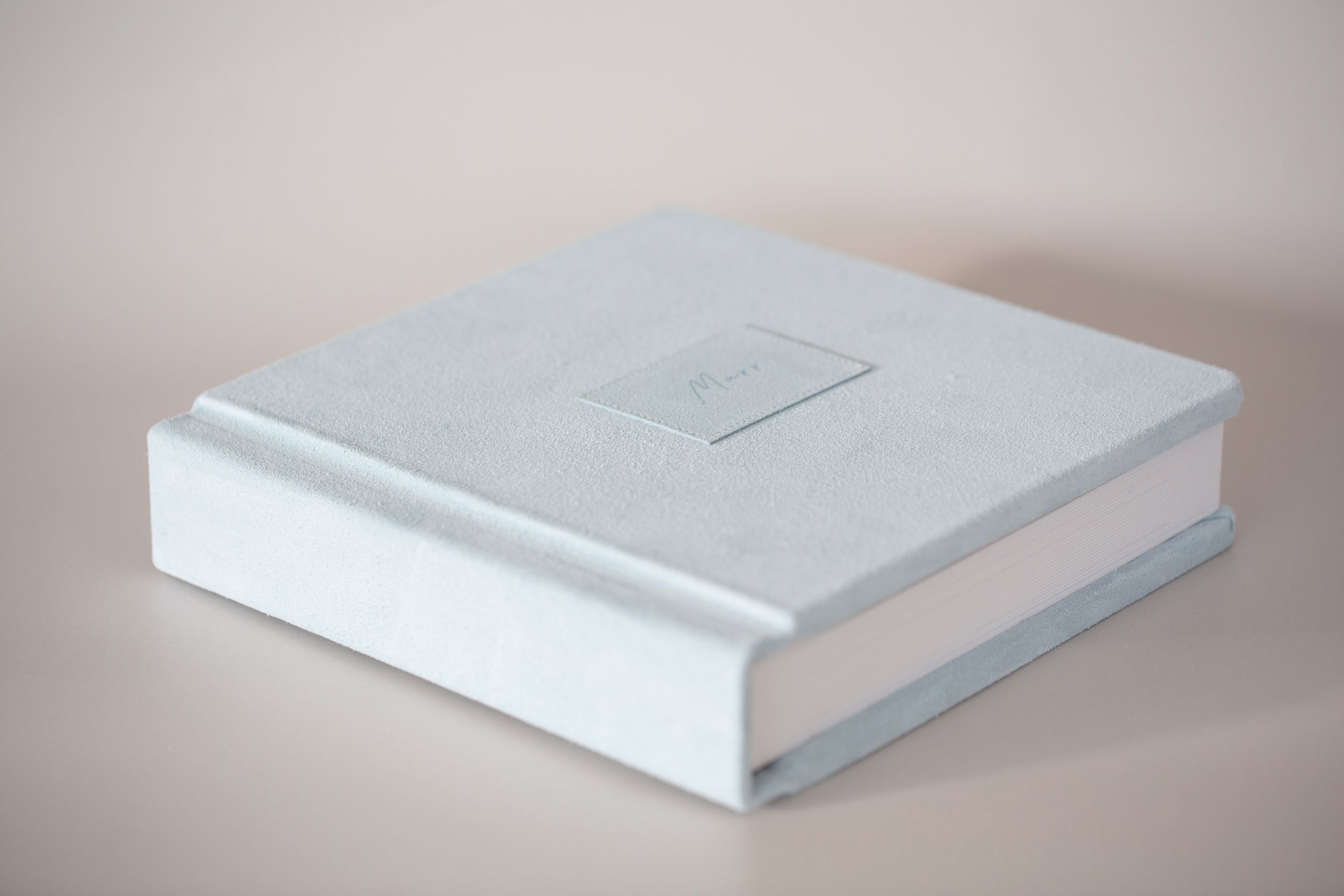 White hardcover book with minimalist design sits against neutral background.