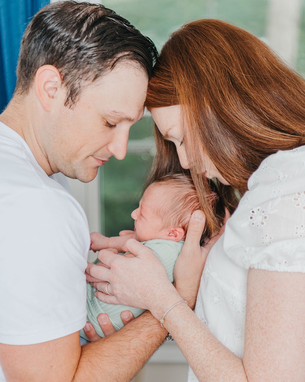 A tender moment as parents lovingly cradle their newborn baby in a soft, intimate setting