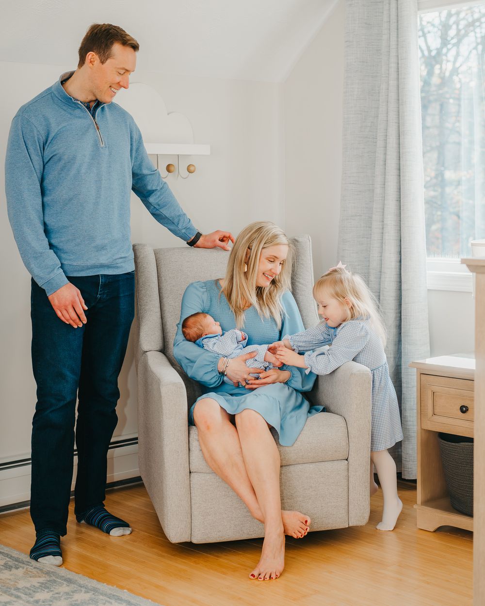 A family gathered in a bright nursery captures tender moments together with a newborn