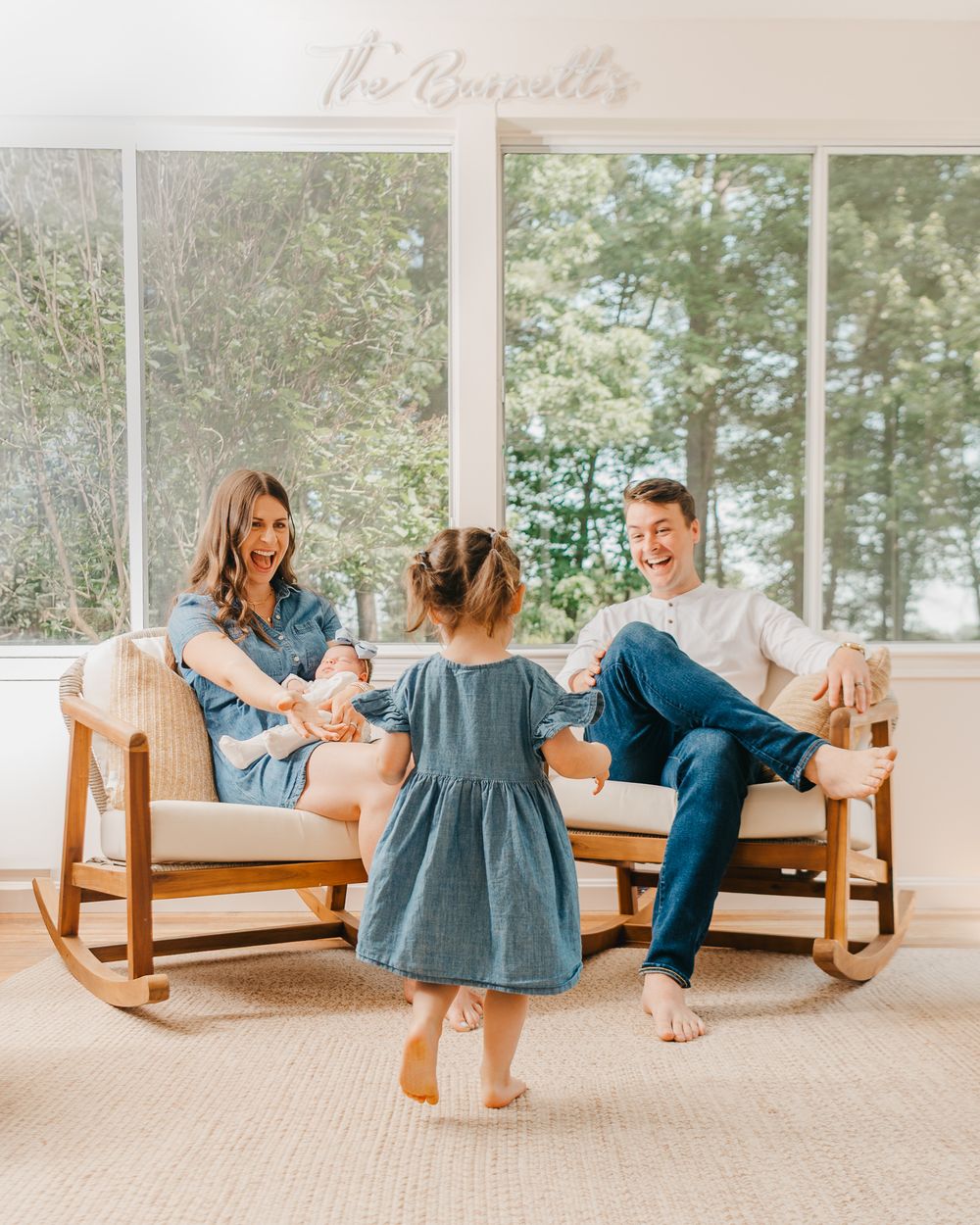 Family enjoying relaxed moments together in their home with sun-filled windows and greenery in the background.
