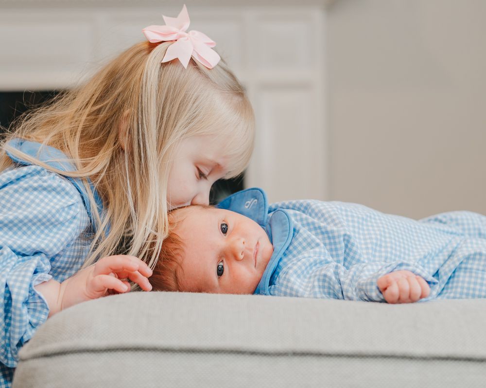 Four cute progressional photos of newborn baby being lovingly kissed while laying on soft bedding.