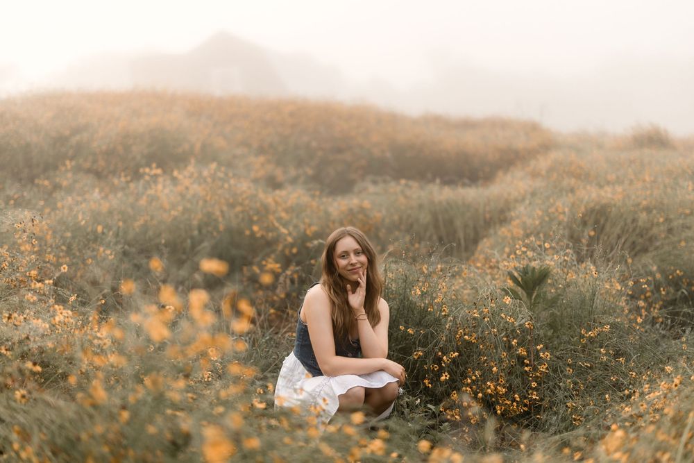 People enjoying themselves in fields of vibrant orange and yellow wildflowers on a misty afternoon.