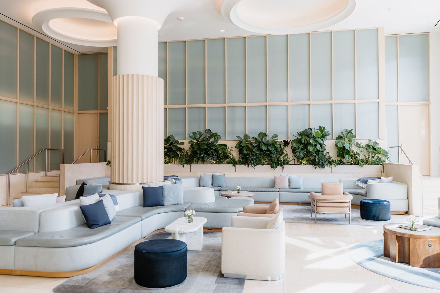 Modern minimalist lobby interior with cylindrical columns and elegant seating areas bathed in natural light.