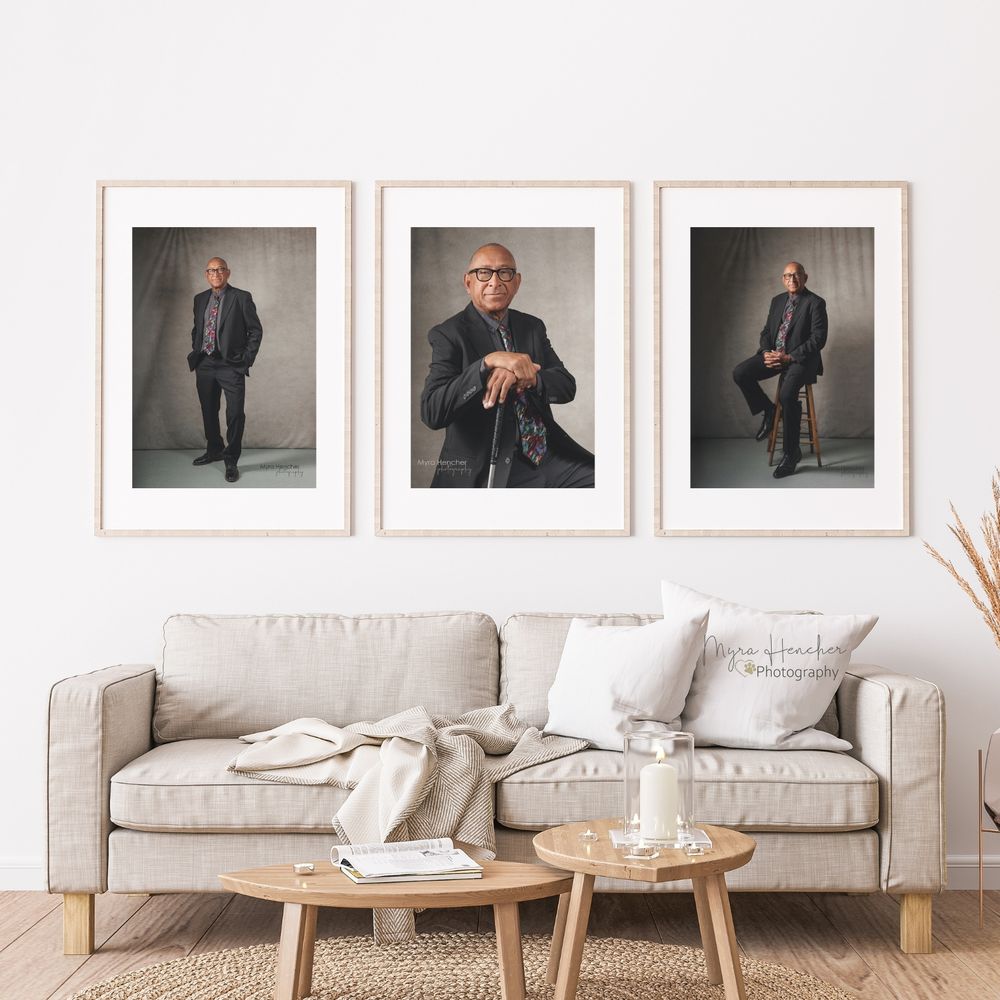 Modern living room interior with three framed portrait photographs above a beige sofa and wooden coffee tables.