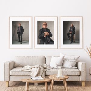 Modern living room interior with three framed portrait photographs above a beige sofa and wooden coffee tables.