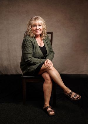 A series of artistic portraits showing someone in a green jacket and sandals sitting on a dark floor against a textured wall.