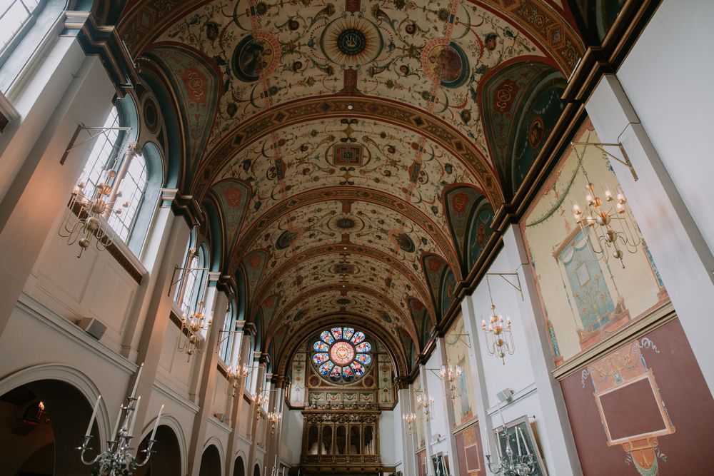 Ornate baroque cathedral interior with arched ceiling, stained glass windows, and gilded decorative details.