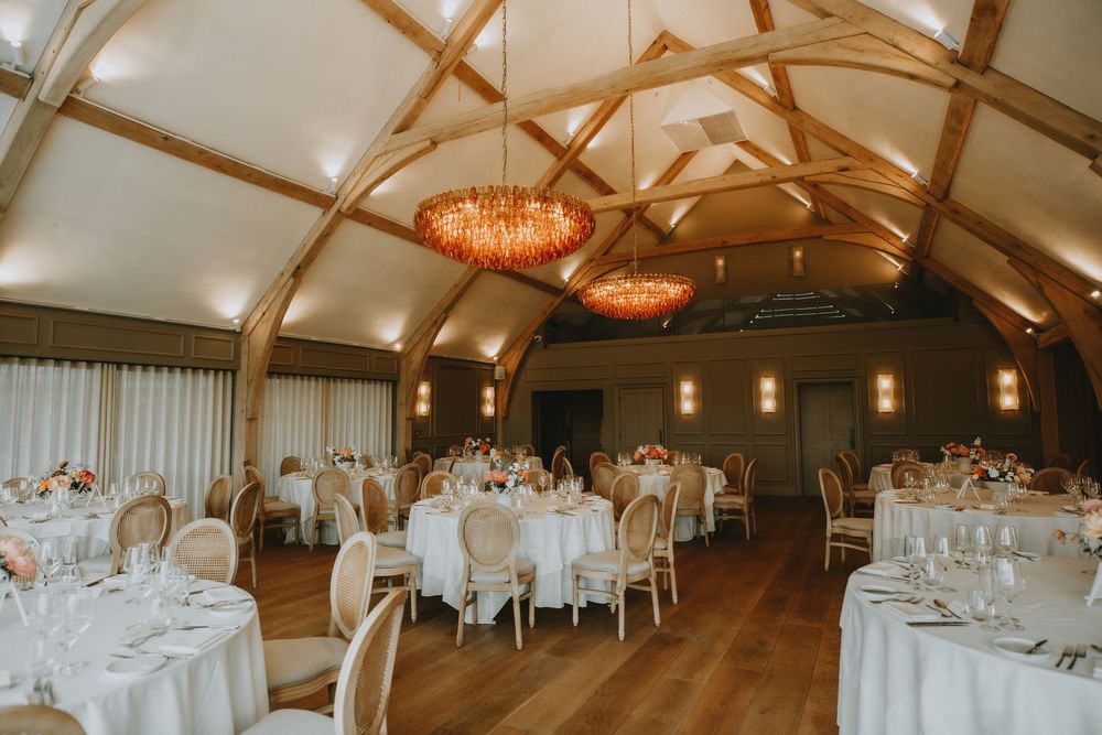 An elegant wedding reception venue with vaulted wooden beams, crystal chandeliers The Marquis Suffolk wedding venue