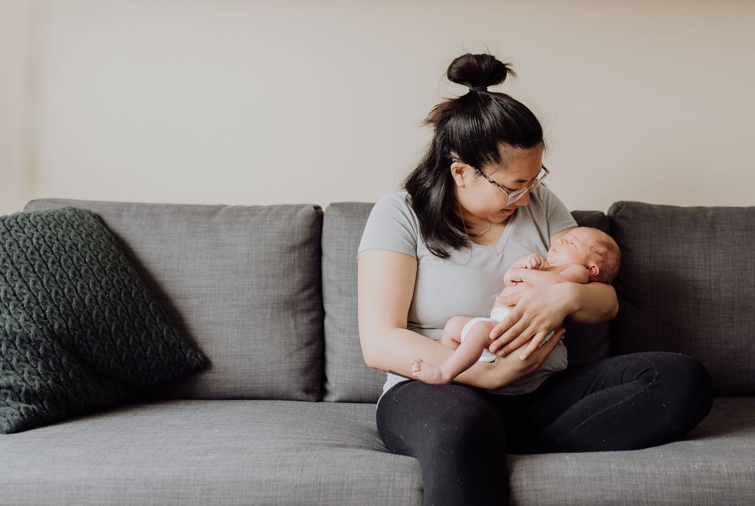 Someone is seating on the couch cradling a baby