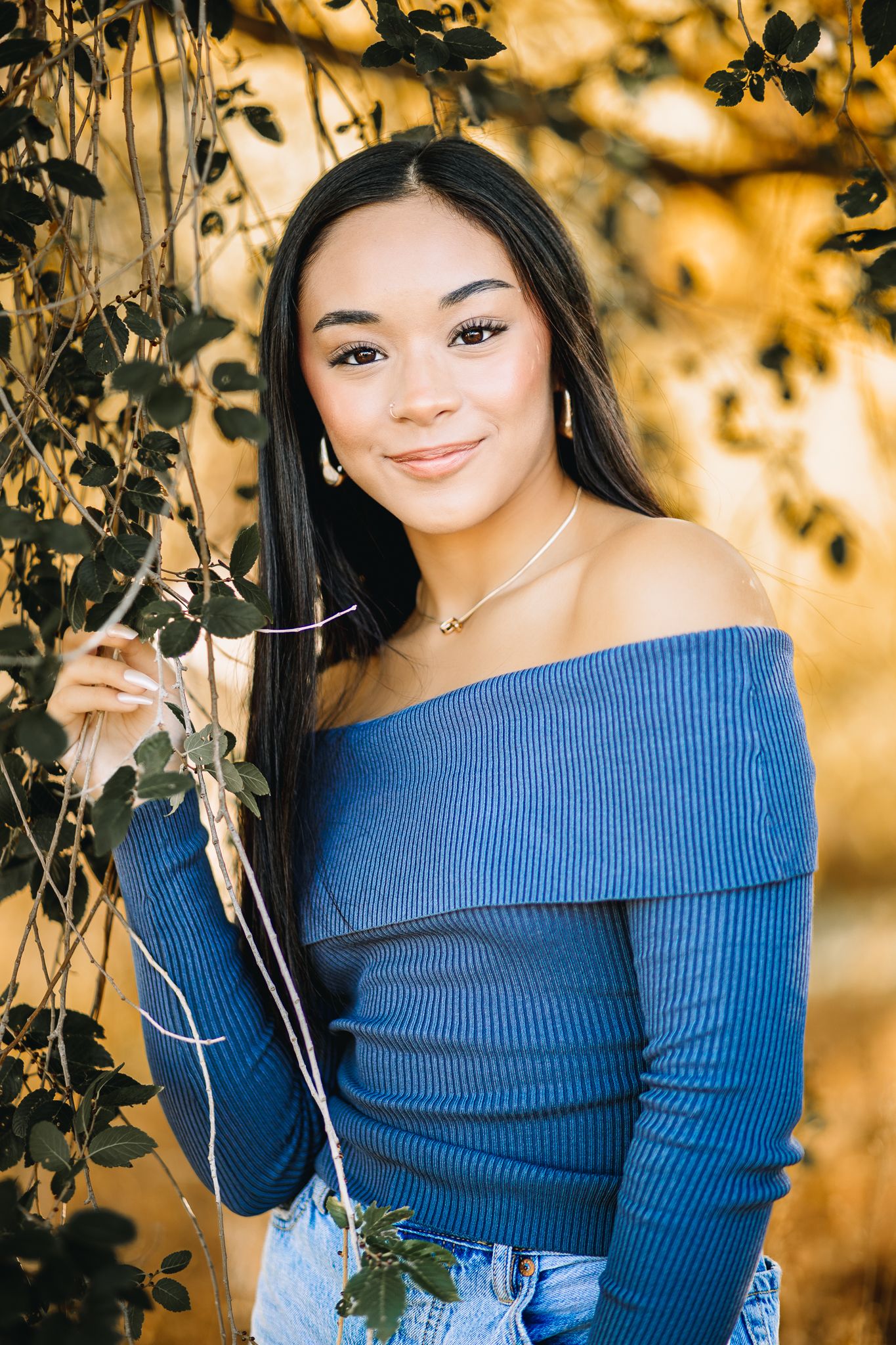 class of 2026 high school senior in Windsor Colorado posing for her senior pictures in a blue shirt softly smiling at the photographer