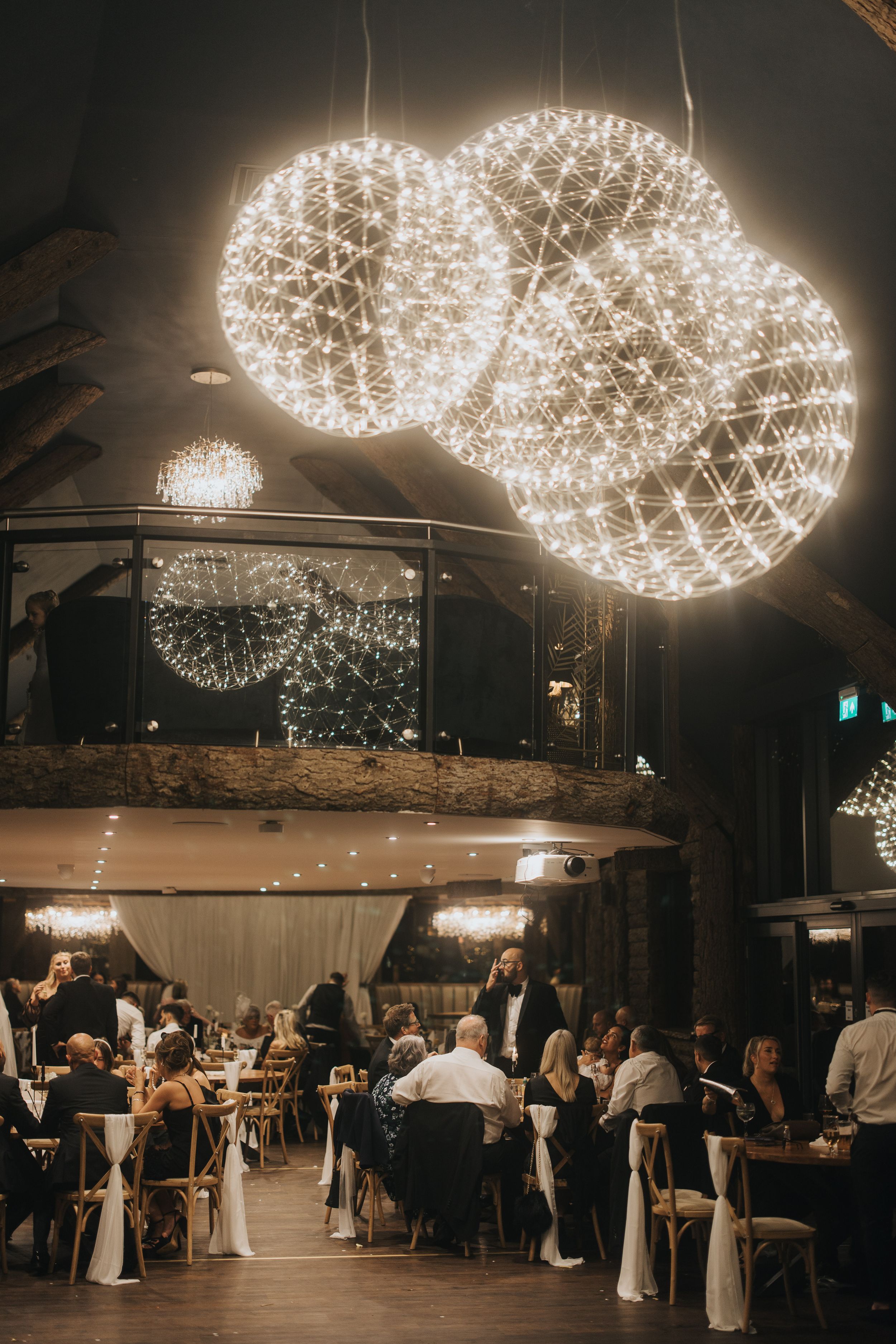Large illuminated spherical light fixtures hang over an elegant dining room at Grand Lodge Oaklands - taken by Grimsby photographer.
