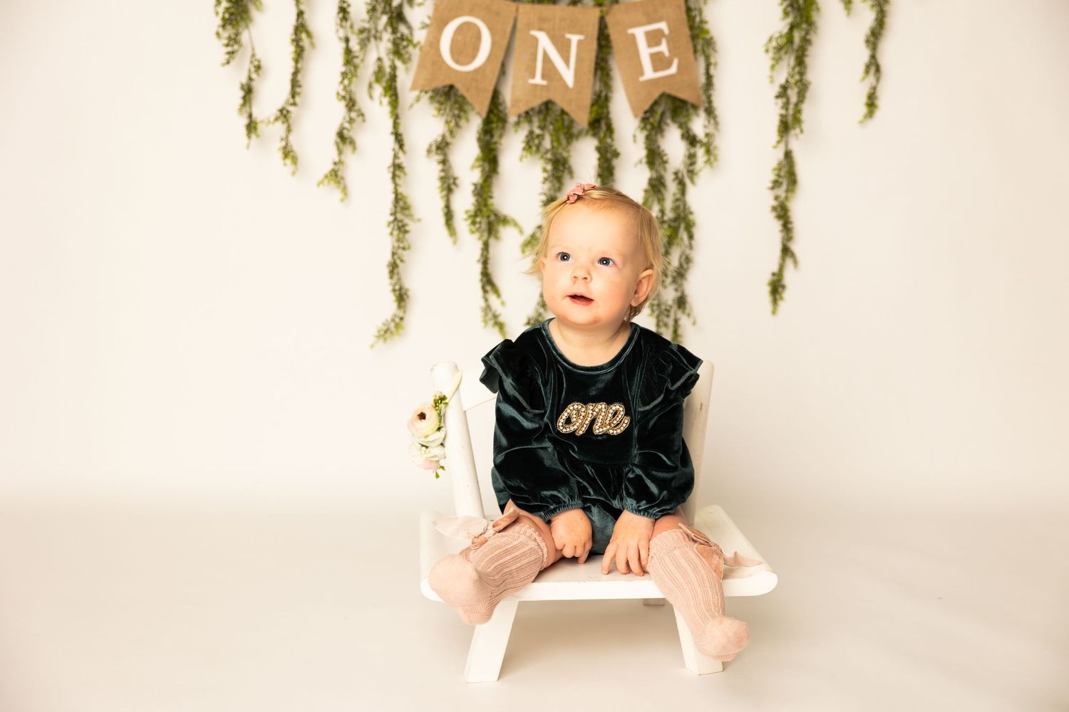 A series of milestone photos showing a baby's first year growth with a gold 'ONE' banner and floral decorations.