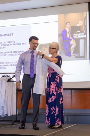 A presentation taking place in a conference room with a projector screen displaying medical or academic content.