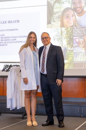 People in professional attire standing together at what appears to be a business presentation or conference.