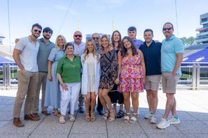 Group of people smiling together on sunny outdoor stadium terrace.