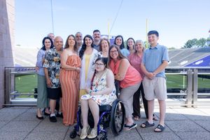 Group photo of people gathered on stadium balcony with wheelchair user in center.