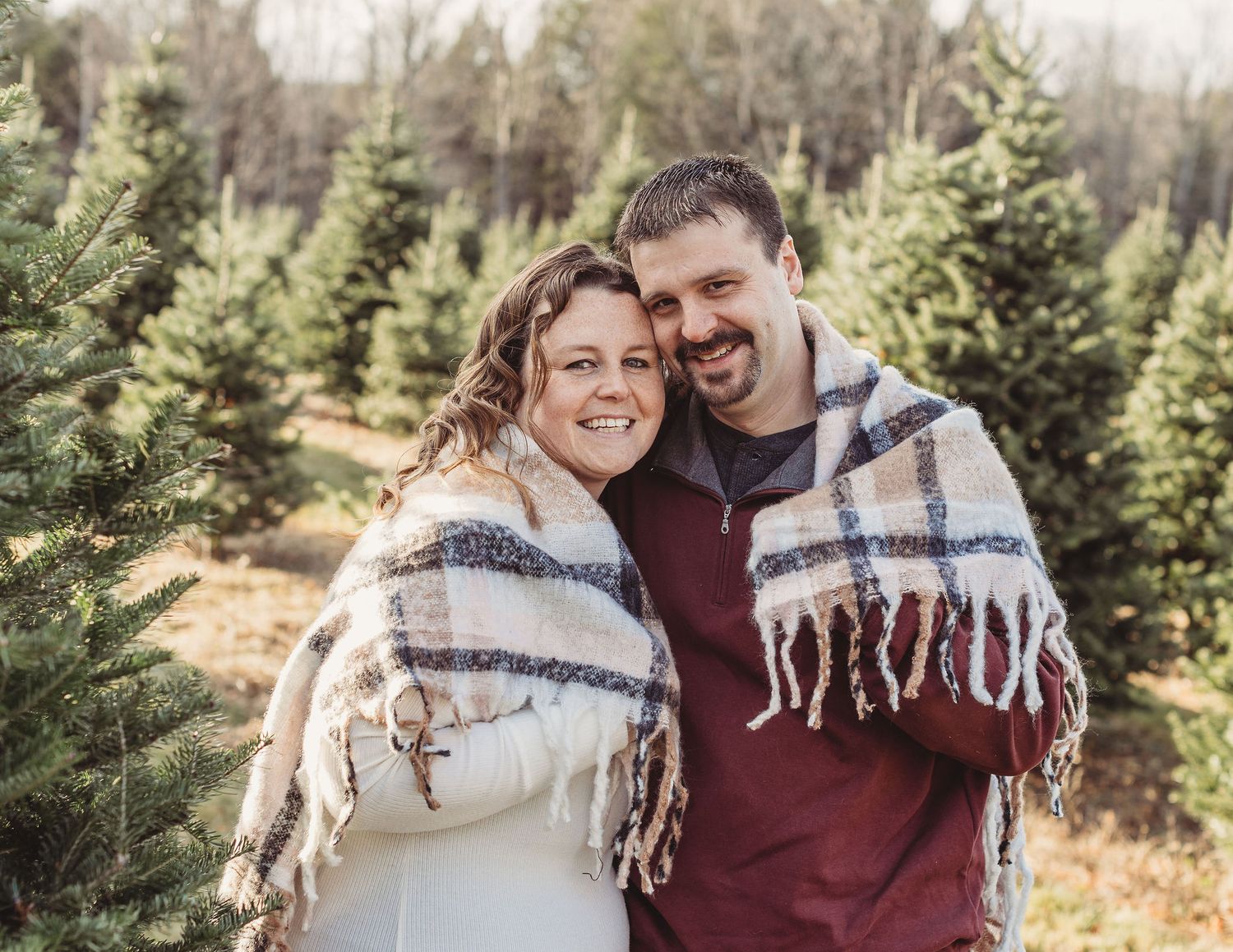 Professional photo of a couple wrapped in a blanket at a treefarm