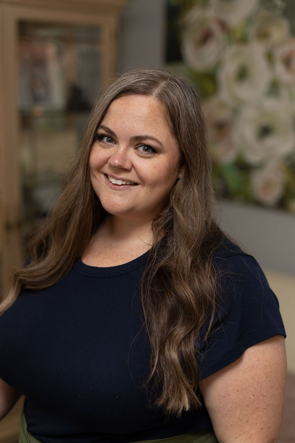 Side view portrait shots of someone with brown hair wearing a navy blue top against a blurred floral background.
