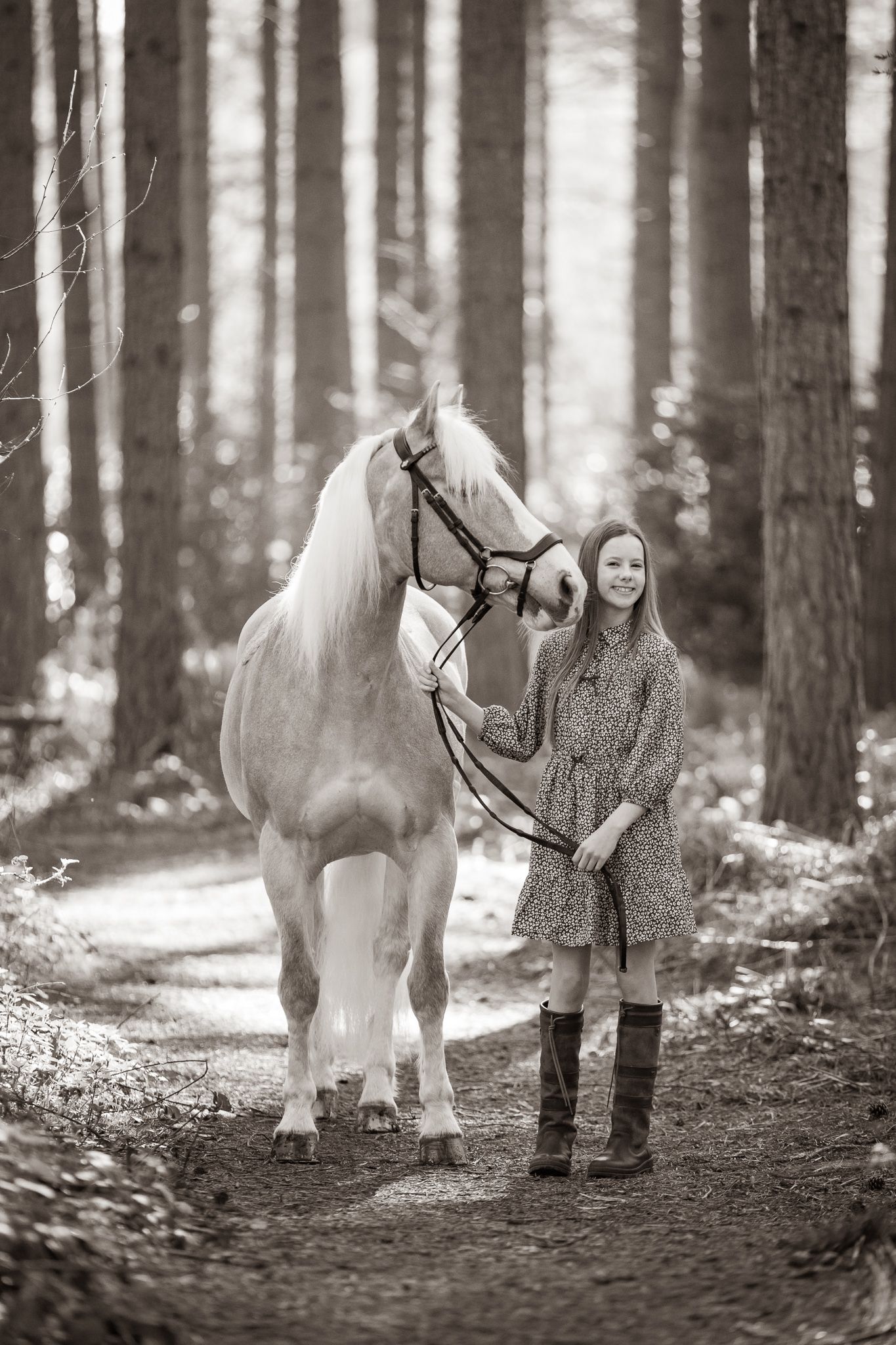 A gentle moment between a rider and dark horse with white blaze in a rustic stable setting, captured in black and white.