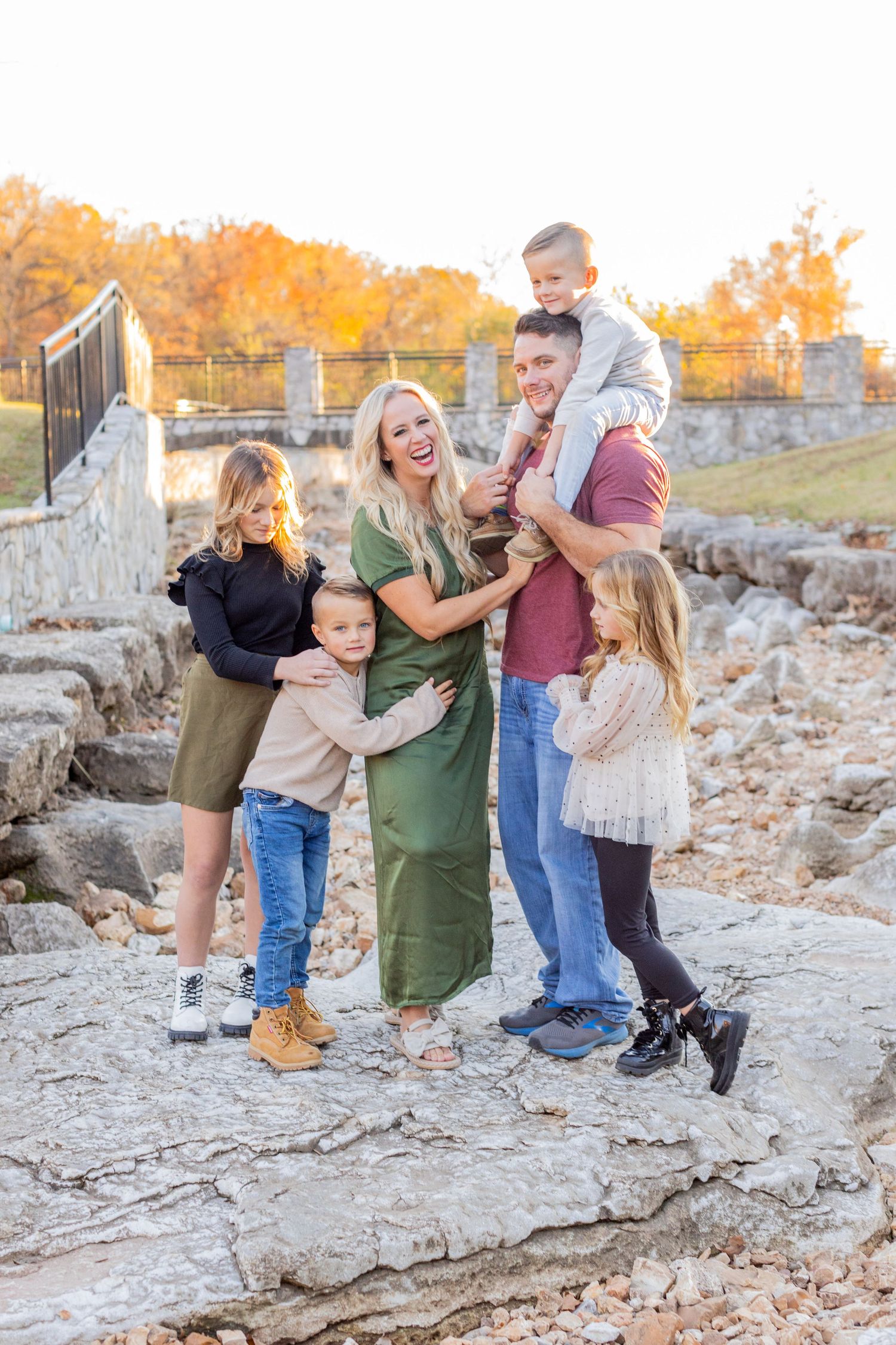 Joyful parent and toddler share sweet playful moments on rocky terrain in outdoor family photoshoot sequence.