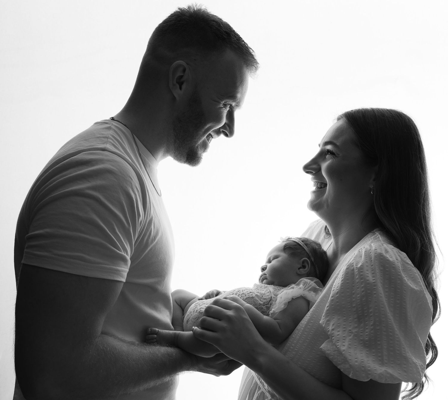 A parent and baby wearing matching pink tulle dresses lay on a pink tulle backdrop in a dreamy portrait setting.