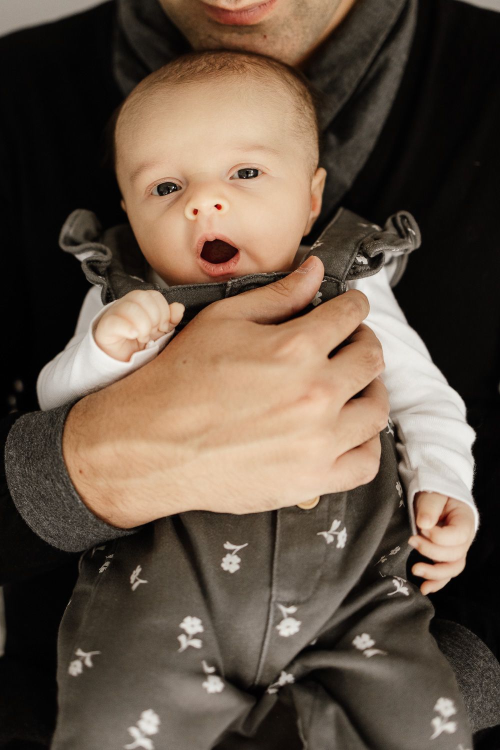 Baby yawns in dad's arms during in-home newborn photo session with Bay Area Photographer Cindy Tucey
