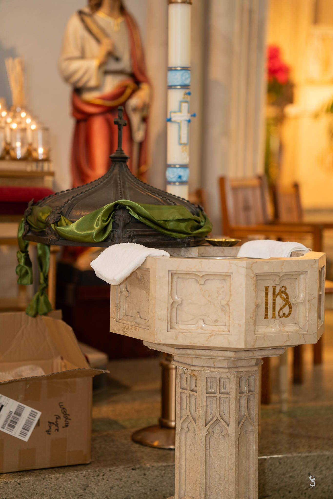 A church baptismal font with ornate decorations and religious symbols in a cathedral setting.