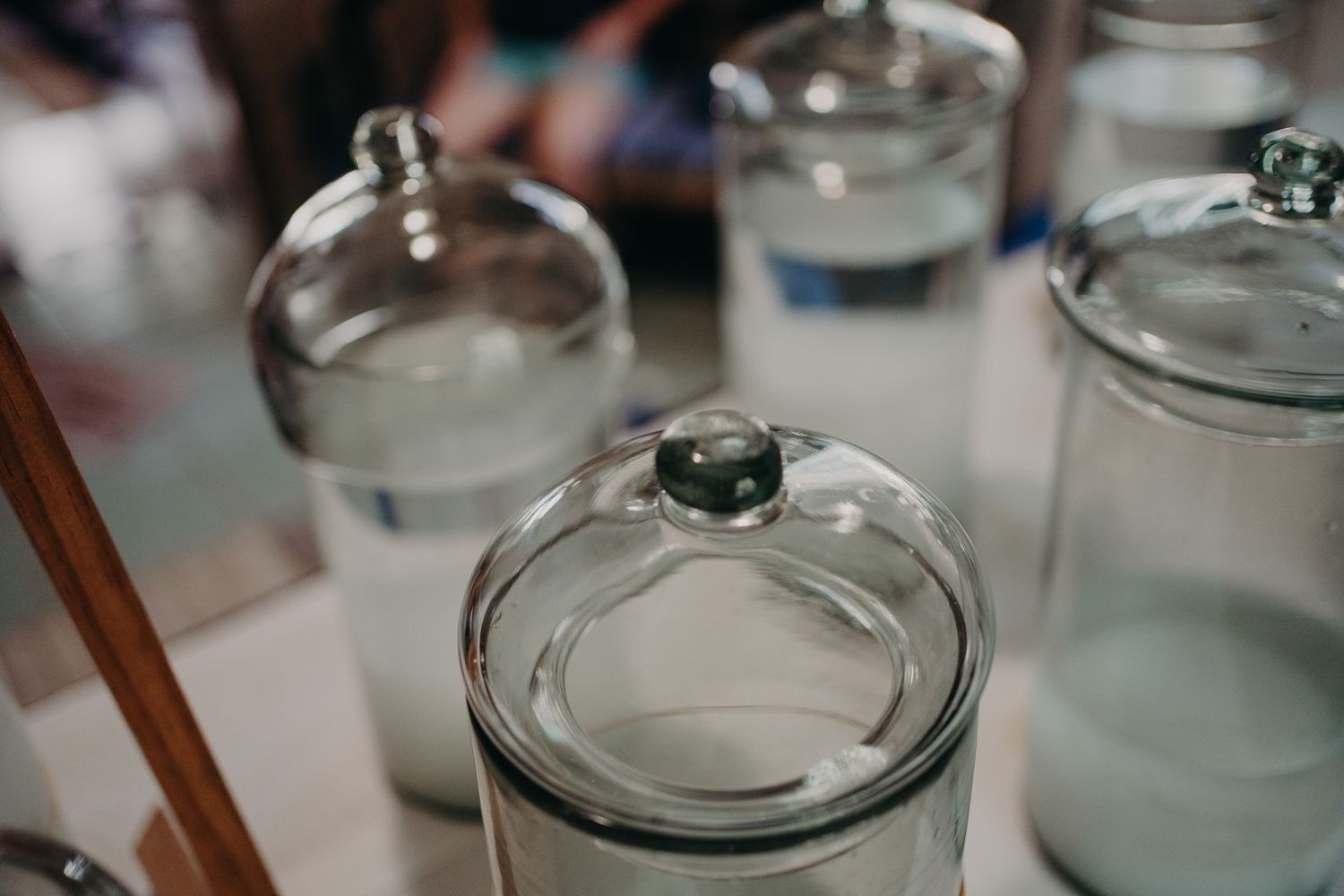 Clear glass jars with domed lids lined up on shelf.