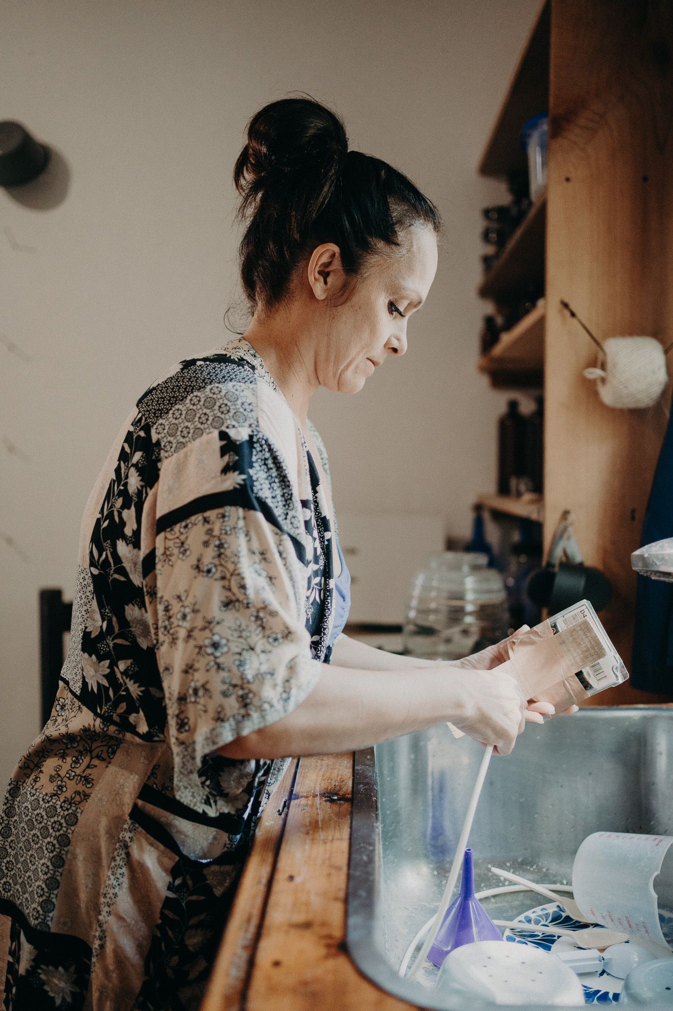 Person in floral dress working with ingredients at a wooden counter.