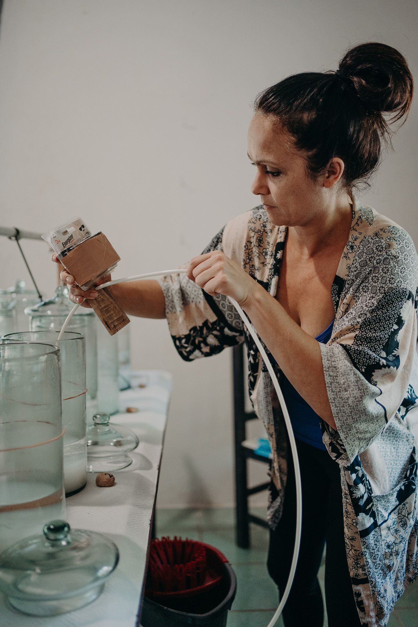 Person in patterned dress carefully measuring ingredients with glass jars on counter.