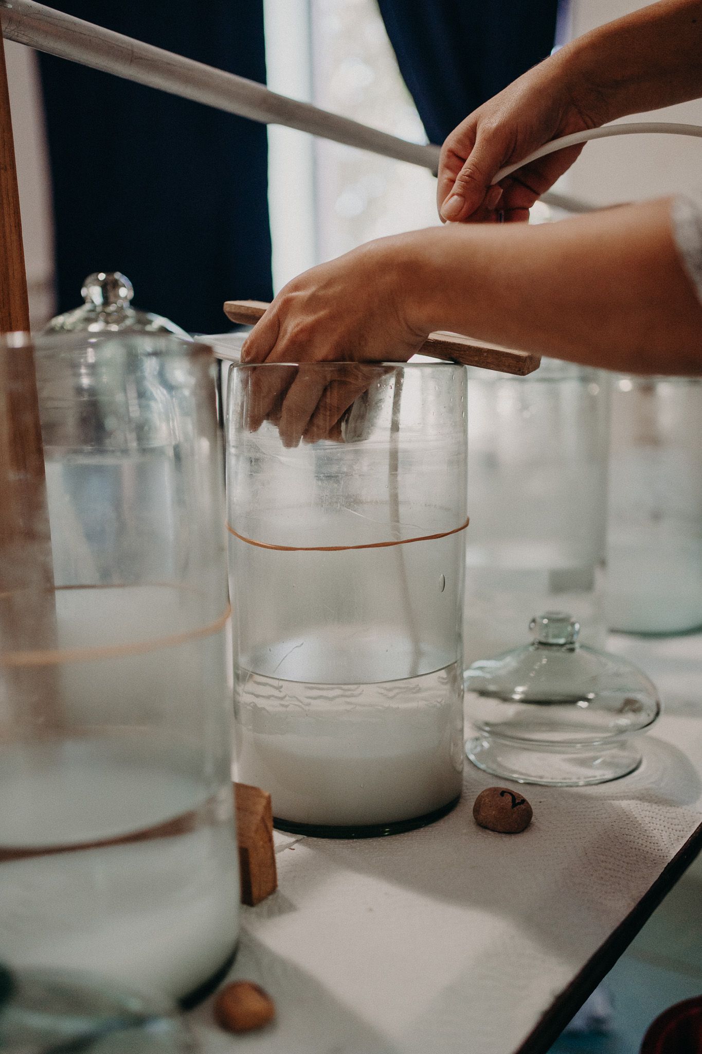 Pouring white liquid into clear glass containers with measuring tools.