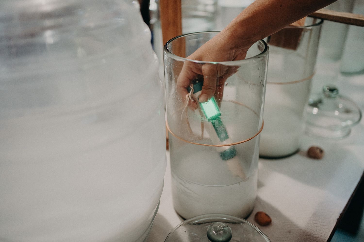 Hands pouring liquid between glass containers in laboratory-style setup.
