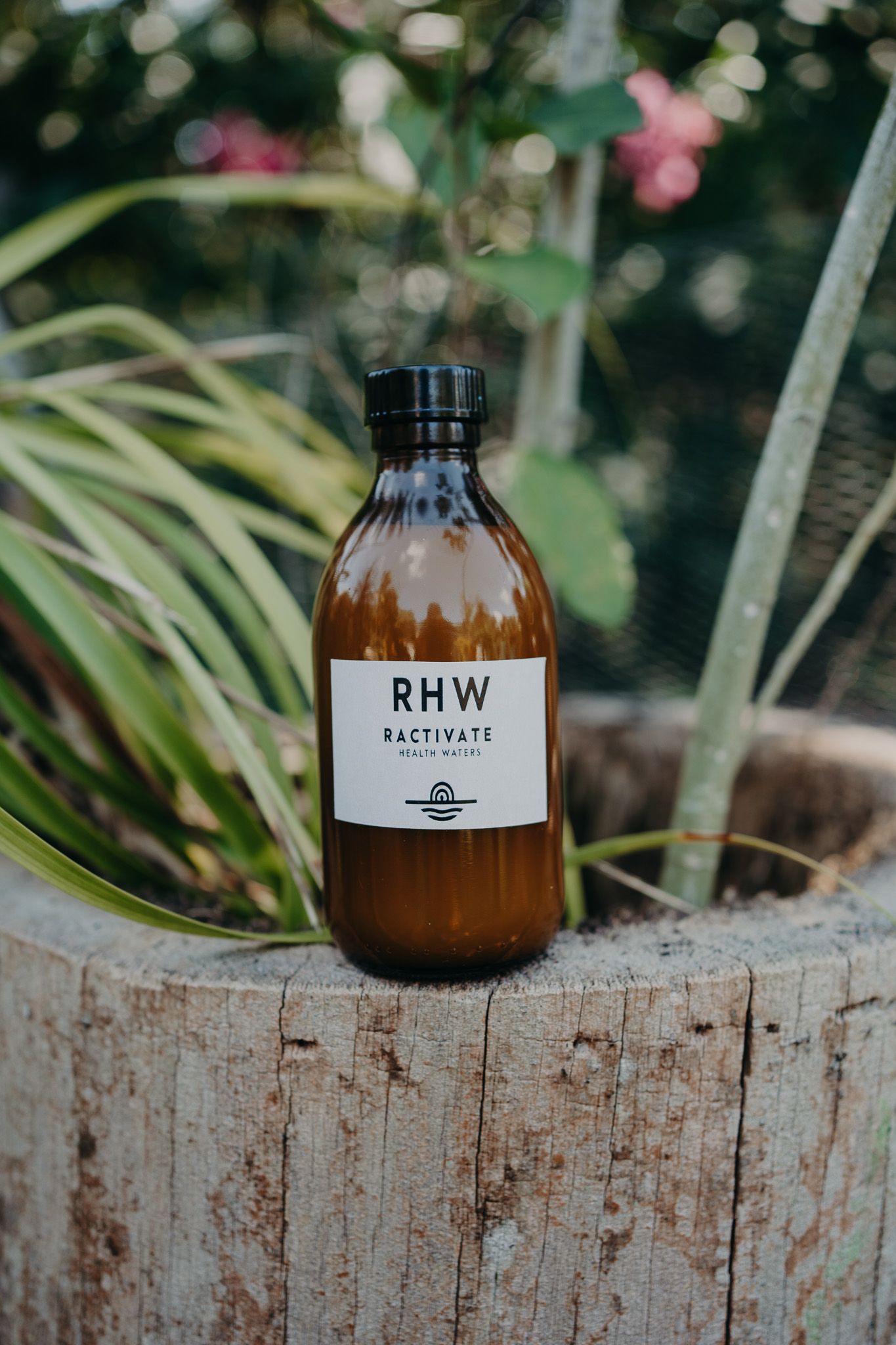 Brown glass bottle labeled RHW Reactivate placed on rustic wooden surface photoshoot in Puerto Morelos.