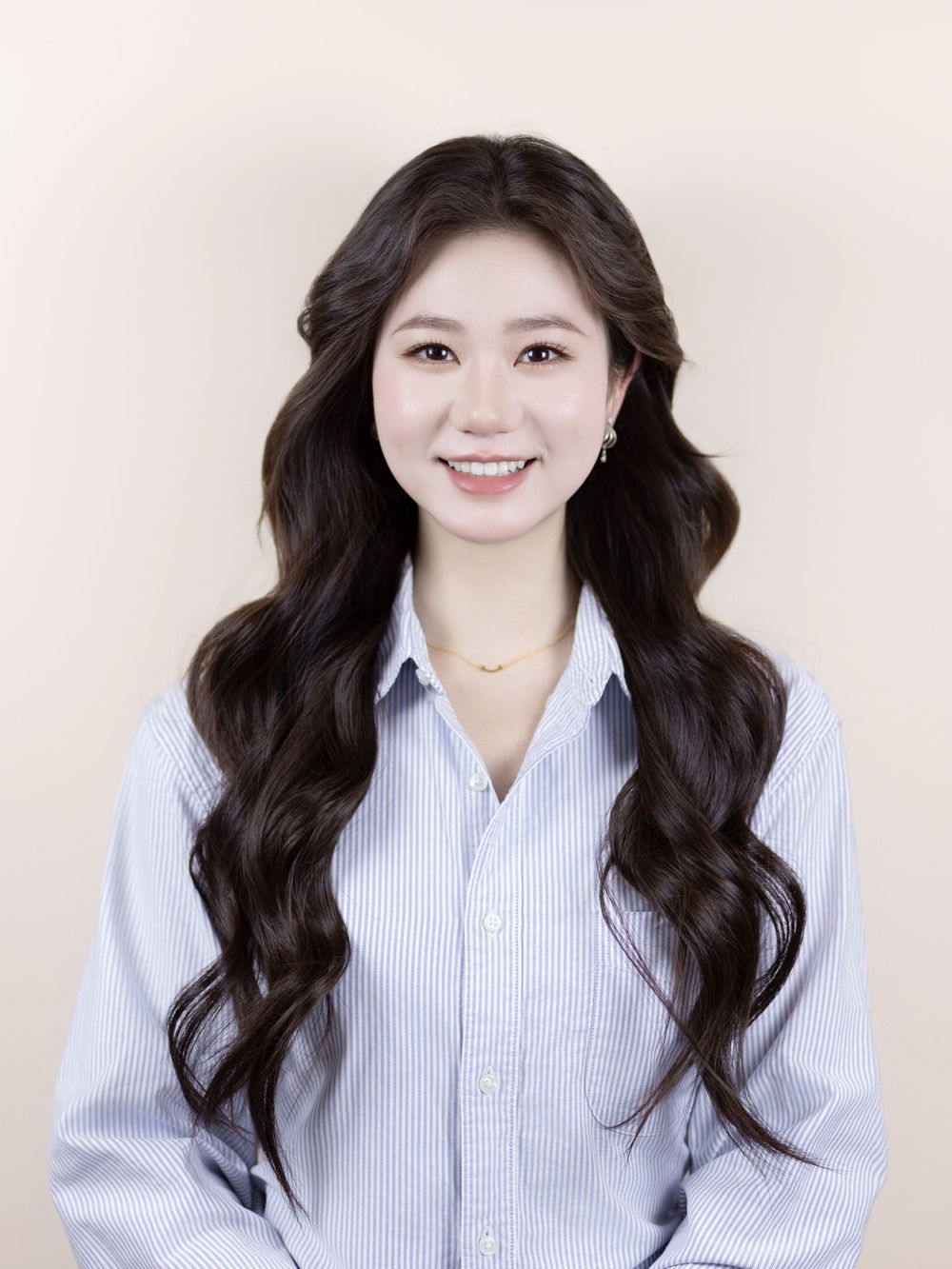 Professional headshot featuring elegant waves and a light blue collared shirt.