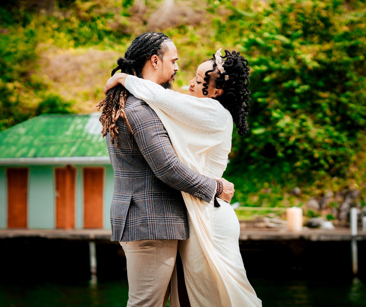 A romantic wedding moment captured outdoors with a rustic green building in the background.