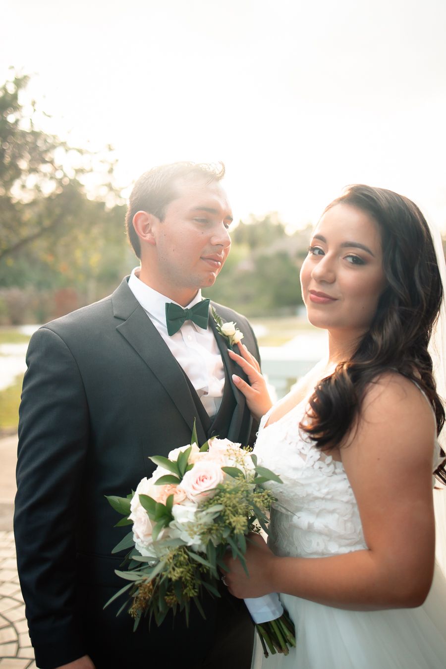 Elegant wedding portrait with bride holding white bouquet next to groom in black tuxedo.
