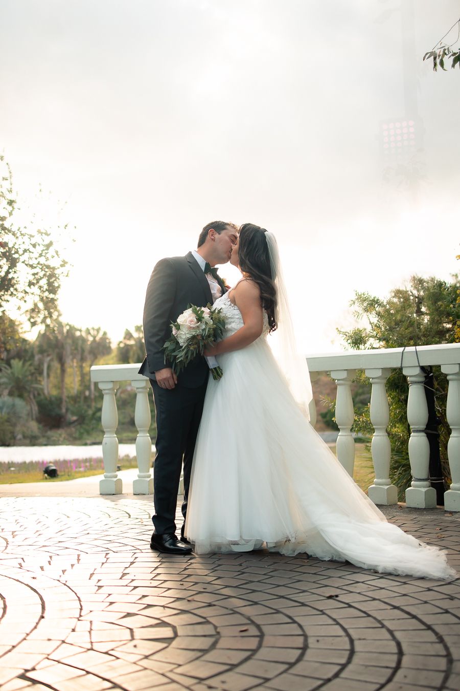 Wedding couple embraces on decorative stone patio during golden hour photoshoot.