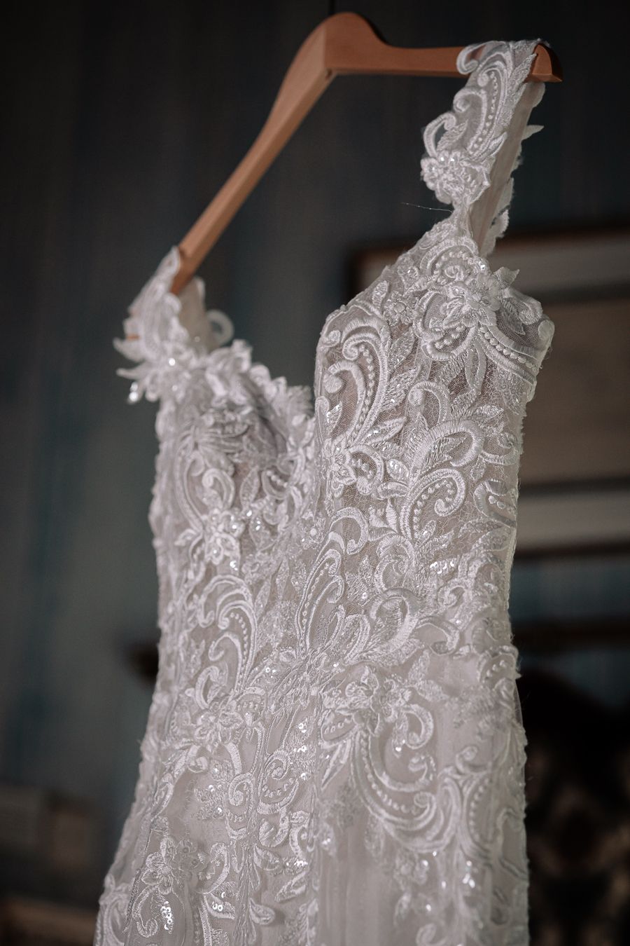 Detailed close-up of intricate lace pattern on white wedding dress bodice.