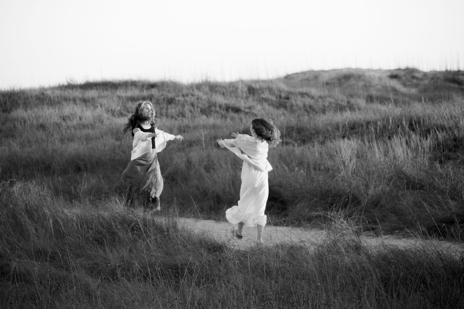Two people dancing in a meadow captured in black and white.