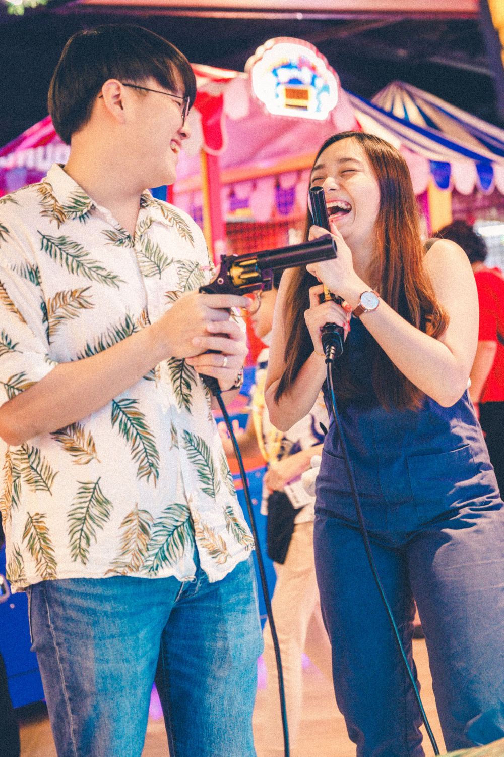 A couple enjoys karaoke together at a carnival-themed arcade.