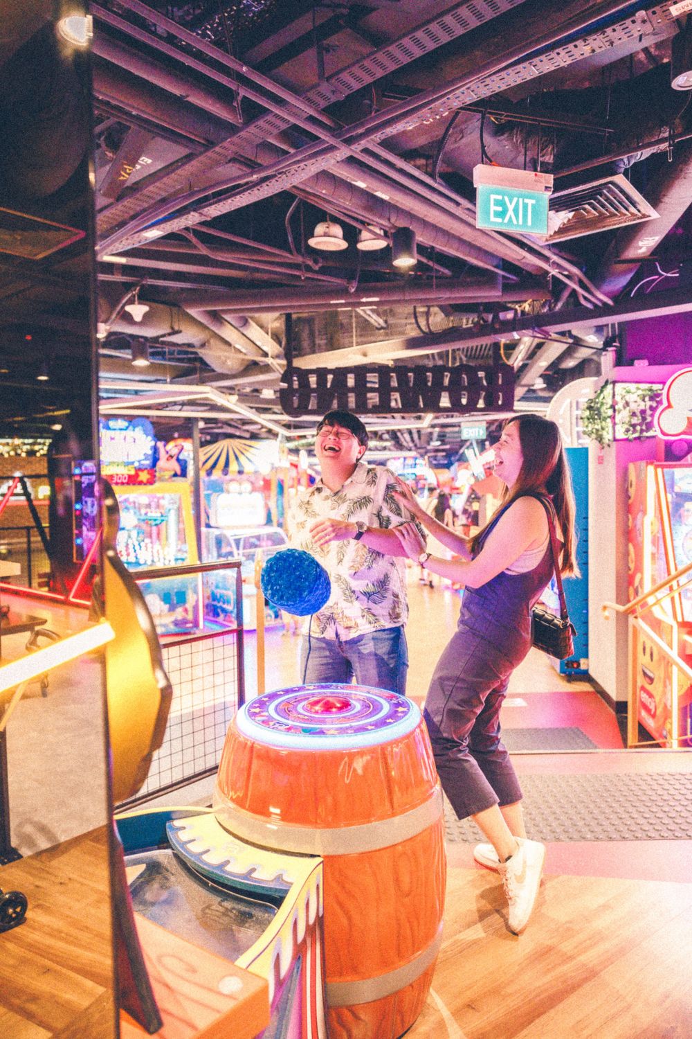 Two people enjoy playing arcade games in a vibrant indoor entertainment center.