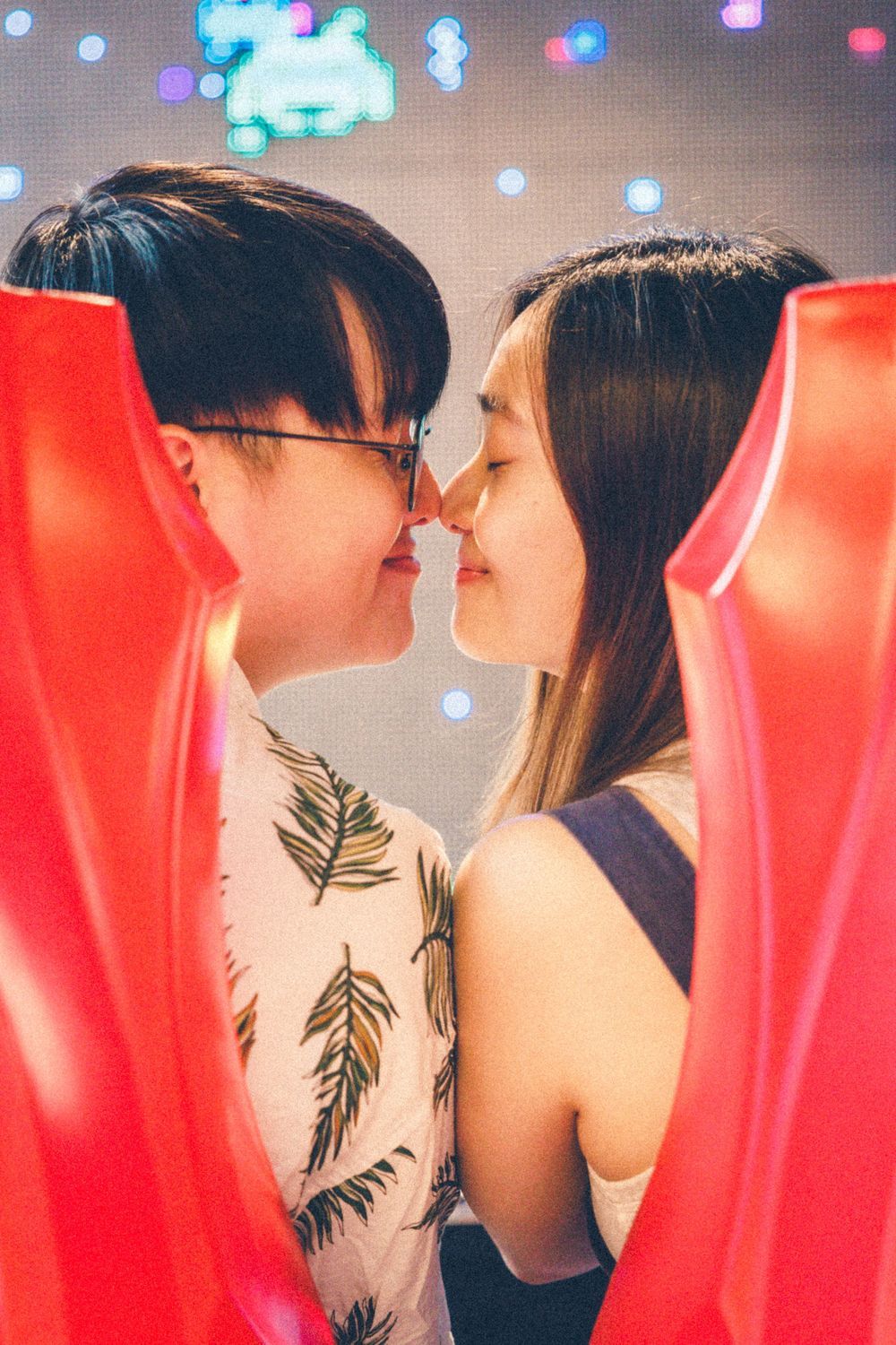 A romantic moment between a couple framed by red arcade machine panels.